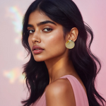 Load image into Gallery viewer, A woman wearing gold-tone metal earrings with a double-layered circular design, resembling the sun's rays, set against a pink background with bokeh lights.