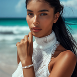 Load image into Gallery viewer, A woman wearing a white tennis bracelet with emerald-cut cubic zirconia stones, posing by the beach.