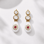 Load image into Gallery viewer, Pair of earrings with gold and white design on a light background