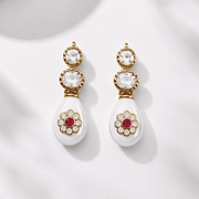 Pair of earrings with gold and white design on a light background