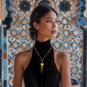 A woman wearing a black sleeveless top and a gold-colored necklace with a quartz-style dagger pendant.