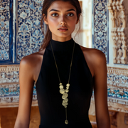 A woman wearing a black halter top and a gold-colored necklace with round disks arranged in clusters.