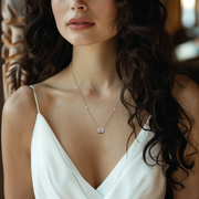 A woman wearing a white dress and a silver necklace with an emerald-cut lab-grown stone pendant.
