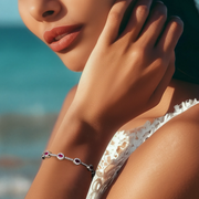 A close-up image of a woman's hand wearing a Radiant Red Riviera Silver Bracelet with oval red stones and lab-grown stones set in silver.
