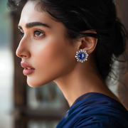 A woman wearing a silver and blue iridescent earring with a starburst design.